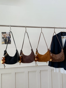 Row of suede half-moon bags in black, brown, and leopard print with bear charms