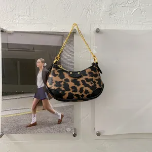 Détail du sac léopard avec bandoulière chaîne dorée sur un présentoir minimaliste
