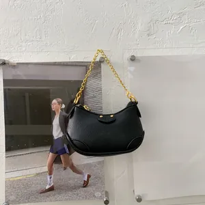 Gros plan du sac hobo noir avec texture cuir grainé et chaîne dorée épaisse