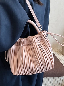 Pink pleated bucket bag with cylinder handle and crossbody strap for modern women