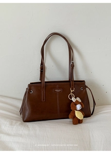 Detail view of dark brown retro shoulder bag with matte leather finish and bear charm