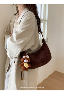 Detail of dark brown matte crescent bag featuring a cute plush bear charm accessory