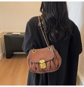Detailed macro shot of vintage brown pleated suede shoulder bag with metal buckle closure