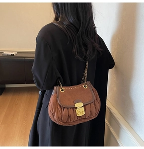 Detail of vintage brown suede shoulder bag with gold rivets and metallic lock on strap