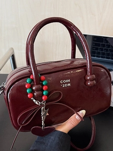 Glossy burgundy patent leather pillow bag with gold logo and heart charm detail