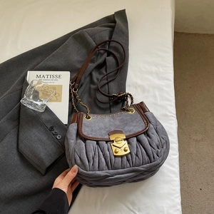 Detail of gray suede pleated bag with brown leather trim and vintage gold lock hardware