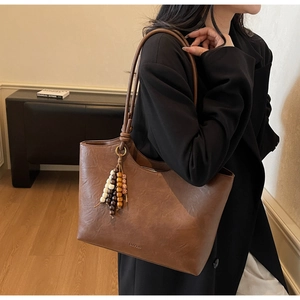 Close-up of brown faux leather tote with colorful bead charm and textured finish