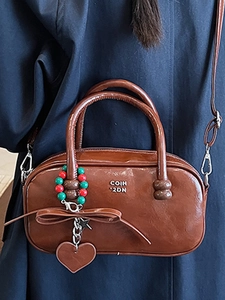 Brown vintage leather pillow handbag with bow detail and adjustable shoulder strap