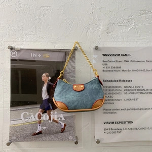 Détail du sac sous l'aisselle en denim avec garniture en cuir et chaîne dorée
