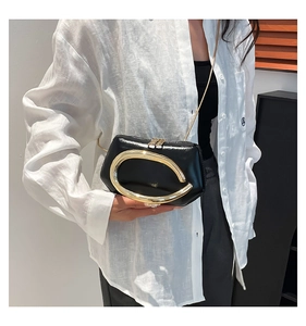 Detail of a vintage black glossy mini bag with a large gold metal handle and chain strap