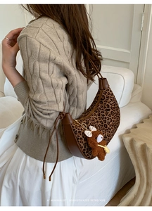 Detail of leopard print crescent bag with leather trim and plush bear accessory