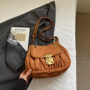 Detailed close-up of caramel pleated suede bag with vintage gold clasp and leather strap