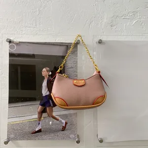 Détail du mini sac demi-lune en cuir rose grainé avec poignée en chaîne dorée brillante