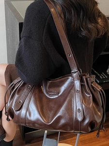 Deep brown glossy oil wax leather shoulder bag with wide adjustable strap on model