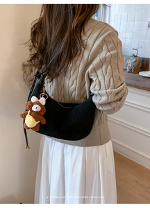 Detailed view of black suede hobo bag with a cute plush bear pendant accessory