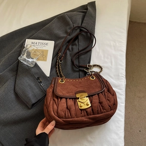 Close-up of vintage brown suede pleated shoulder bag with gold metal buckle and leather chain
