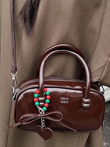 Glossy dark brown pillow bag with heart charm and beaded strap, worn with autumn outfit