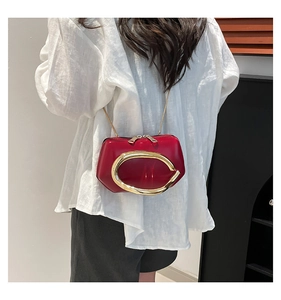 Detailed view of the red patent leather mini bag with gold C-shaped metal buckle and chain