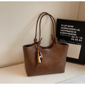 Detail of vintage brown leather tote bag with unique wood bead tassel and long straps