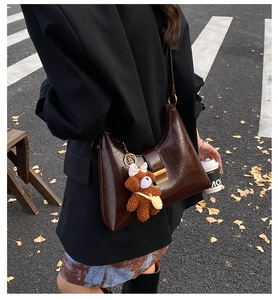 Detail of dark brown oil wax leather underarm bag with a cute brown plush bear charm