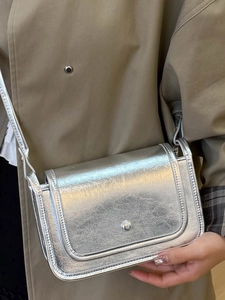 Piccola borsa a tracolla argento metallizzato con fibbia su trench color kaki