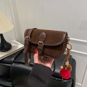 Close-up of retro brown faux suede shoulder bag with decorative charms and gold buckle detail