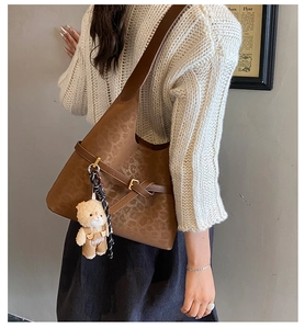 Detalle de bolso de hombro con estampado de leopardo, hebilla dorada y oso de peluche
