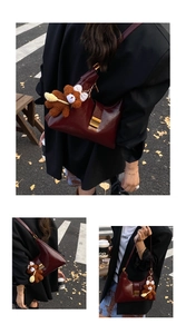 Detail of burgundy leather shoulder bag featuring a gold buckle and brown plush bear charm