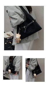 Detalle del bolso tote negro con textura de leopardo, hebilla y colgante de oso