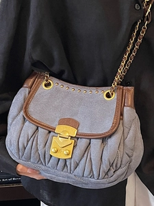 Vintage pleated shoulder bag with brown leather trim and gold chain strap held by model