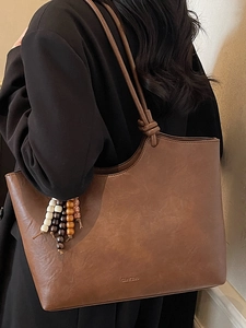 Minimalist brown faux leather tote bag with wooden bead charm for autumn commuter style