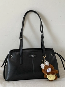 Minimalist black faux leather shoulder bag with drawstring and plush bear charm