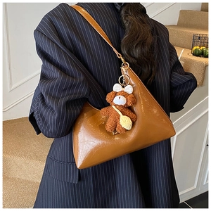 Detail of vintage brown geometric shoulder bag with a plush bear charm on stripe suit