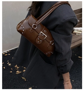 Detail of vintage brown leather underarm bag with silver studs and decorative buckle