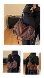Detailed view of the dark brown matte suede shoulder bag with dual handles and long strap