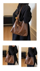 Detail of a brown glossy leather tote bag with wooden bead charm and minimalist handle