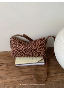 Gros plan du sac bandoulière léopard avec bandoulière en cuir sur un bureau en bois vintage