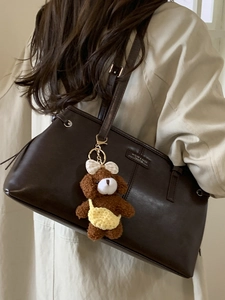 Brown leather shoulder bag with plush dog charm and adjustable strap for women