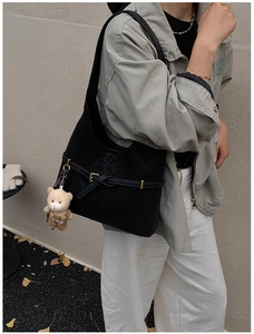 Detalle de bolso tote negro de ante con estampado de leopardo y colgante de osito mono
