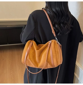 Close-up of brown suede Boston bag showing detailed stitching and silver metallic hardware