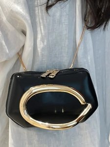 Chic black patent leather mini square bag with bold gold C-shaped metal handle and chain strap