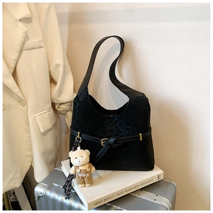 Detalle del bolso hobo negro con estampado de leopardo, colgante de oso y hebilla de cuero