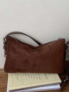 Sac sous le bras rétro en daim marron mat avec boucles argentées sur table en bois