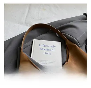 Détail d'un sac sous le bras en cuir marron avec logo métallique sur fond texturé