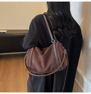 Detail of dark coffee suede tote bag with silver metal buckles on a shoulder strap
