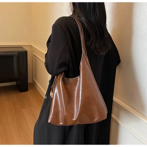 Detail view of large dark reddish-brown leather tote bag worn by model in minimalist room