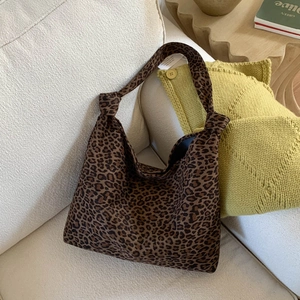 Detail der Leopardenmuster-Canvas-Tasche mit geknotetem Griff auf einem beigen Stoffsofa