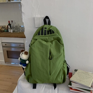 Detail view of grass green waterproof nylon backpack featuring a cute panda plush charm