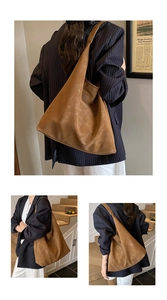 Détail d'un grand sac fourre-tout marron en cuir mat avec logo métallique et bandoulière large