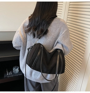 Detail shot of large black suede hobo bag with dual handles and crossbody strap